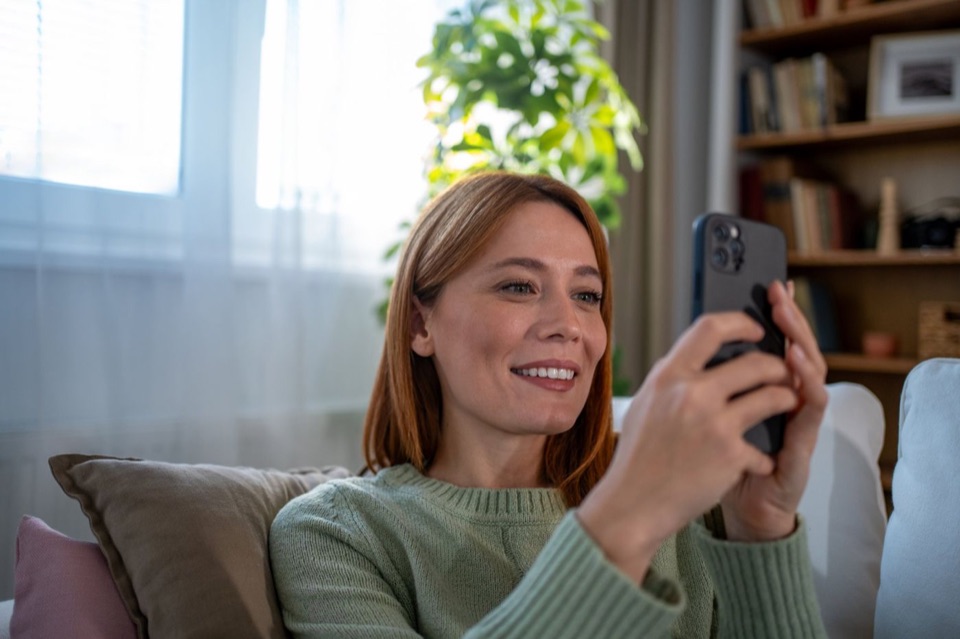 Woman on her sofa answering a health questionnaire on her phone